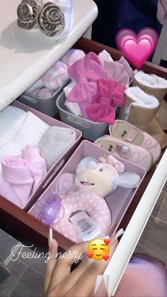 a drawer filled with lots of baby items next to a person holding a toothbrush