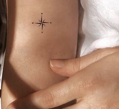 a woman's arm with a small compass tattoo on the left side of her body