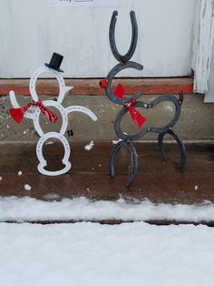 two metal snowmen with hats and bows on their heads are standing in the snow