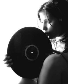 black and white photograph of a woman holding a record in front of her face with light coming through the window behind her