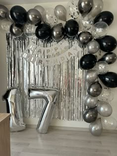 the balloon arch is decorated with black and silver balloons