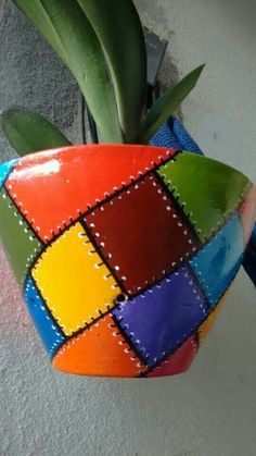 a potted plant that has been painted with squares and dots on the outside, sitting next to a wall