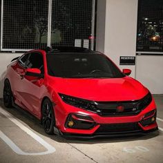 a red car is parked in the parking lot