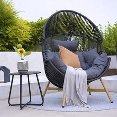 a black wicker chair sitting on top of a blue rug next to a table