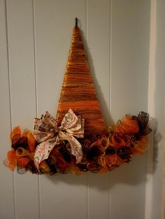 an orange and brown christmas tree decoration hanging on the wall with ribbon around it's base