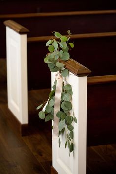 the greenery is tied to the pews at this wedding