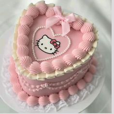 a pink hello kitty heart shaped cake on a white plate with lace around the edges