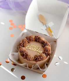 a birthday cake in a box with confetti on the table next to it