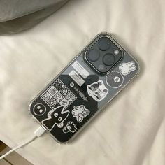 an iphone case with stickers attached to it sitting on a white sheet covered bed