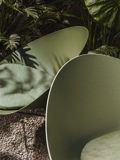 two green chairs sitting next to each other on top of a carpeted floor with plants in the background