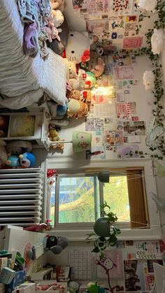 a cluttered kitchen with lots of stuffed animals on the wall and windows above it