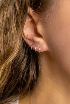 a close up of a woman's ear with two small hoops on it