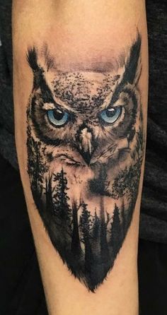 an owl with blue eyes and trees on his arm