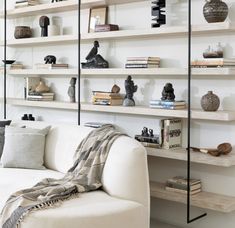 a living room filled with lots of books on shelves next to a white couch and coffee table