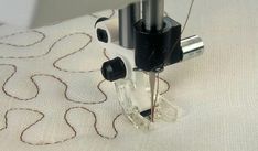 the sewing machine is working on the fabric with it's needle pointed towards the thread