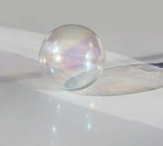 a glass ball sitting on top of a white table next to a black and silver object