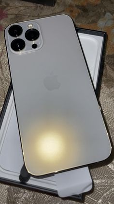 an iphone 11 is sitting on top of a box with its light shining through it