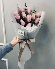 a person holding a bouquet of pink flowers