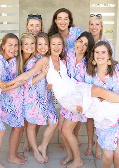 a group of women standing next to each other wearing matching pink and blue robes with palm leaves on them