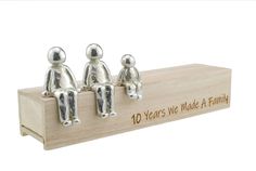 three small silver figurines sitting on top of a wooden box that says 10 years we made a family