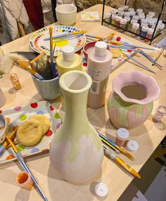 the table is covered with pottery and other crafting supplies, such as paintbrushes