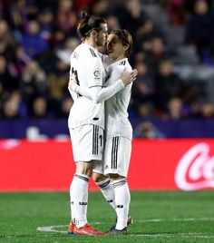 two female soccer players hugging each other on the field