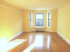 an empty room with hard wood floors and yellow walls