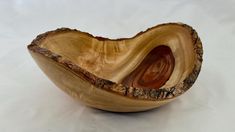 a wooden bowl that is sitting on a white tableclothed surface with wood grain in it