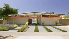 a modern house with grass and trees in the front yard