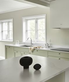 two black vases sitting on top of a white counter in a kitchen next to a sink