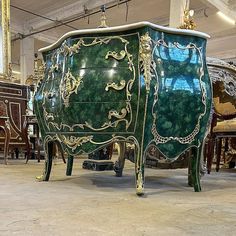 an ornately painted green chest of drawers in a room full of antique chairs and tables