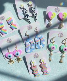 six pairs of earrings are on display in front of a blue background with white and pink designs