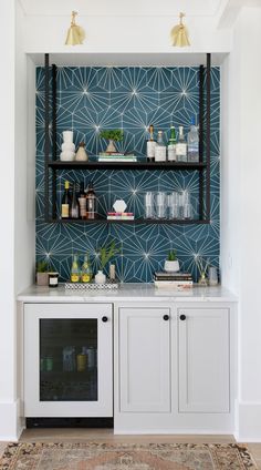 a kitchen with white cabinets and blue wallpaper on the back splash, along with an area rug