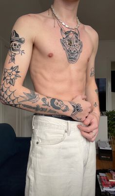 a shirtless man with tattoos on his arm and chest standing in a living room