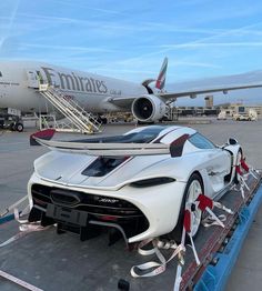 a white sports car being loaded onto an airplane