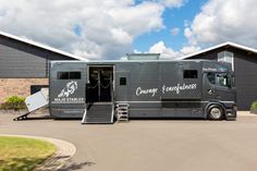 a horse trailer parked in front of a building with stairs leading to the side door