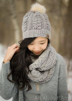 a woman wearing a gray hat and scarf with a pom - pom on it