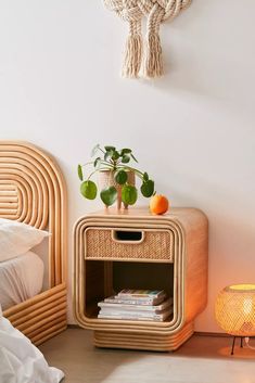 a bedroom with a wicker side table next to a night stand and lamp on the floor