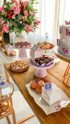 a table topped with lots of different types of cakes and pastries next to a vase filled with flowers