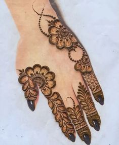 a henna design on the palm of someone's hand, with flowers and leaves