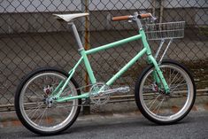 a mint green bicycle parked next to a chain link fence