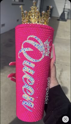 a person holding up a pink can cooler with a crown on it's head