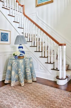 there is a table with flowers on it in front of the stair case and rug