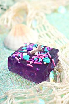 a purple square cake with sprinkles on it sitting on top of a table