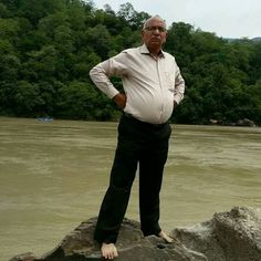 an older man standing on top of a rock next to a river