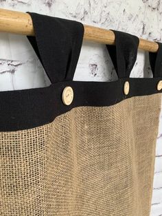 a black and tan curtain hanging from a wooden rod with two buttons on the side