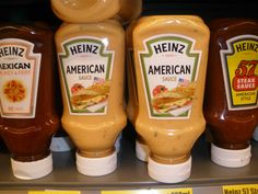 three bottles of heinz's american sauce are on display in a grocery store shelf