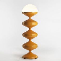 a tall yellow lamp sitting on top of a white floor next to a light bulb