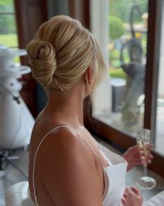 a woman sitting at a table with a glass of wine in her hand and another person standing behind her