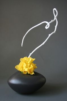 a white wire sculpture with yellow flowers in it